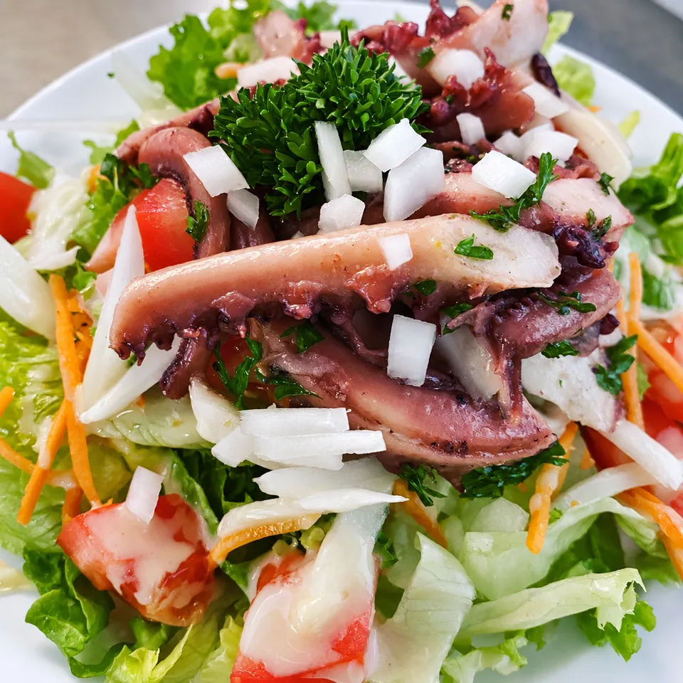 Salade de poulpe avec tomates, oignons et persil.